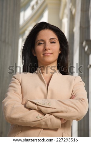 businesswoman in challenging pose between columns looking at you