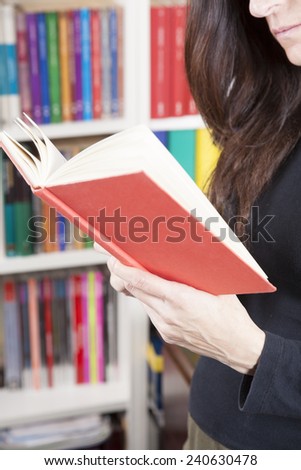 red book in black shirt brunette woman hand over library background