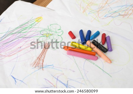 red blue orange pink purple black crayons on baby painting white sheet paper on table inside home