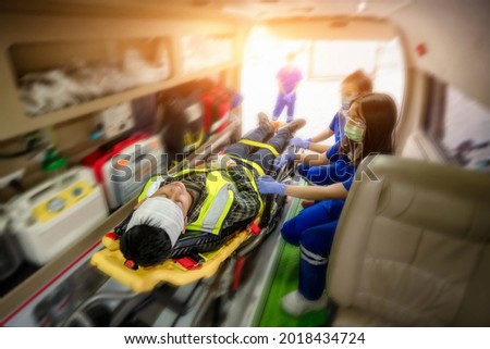 Emergency accident patient Suffered concussion on head lying on stretcher in ambulance. First aid training patient in emergency accident. transfer patient on ambulance. Select focus, add motion blur.
