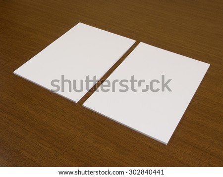 Two blank white papers on a wooden background. Portfolio presentation for graphic designers.