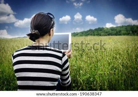 Girl with tablet computer sitting on the grass. Vintage photos.