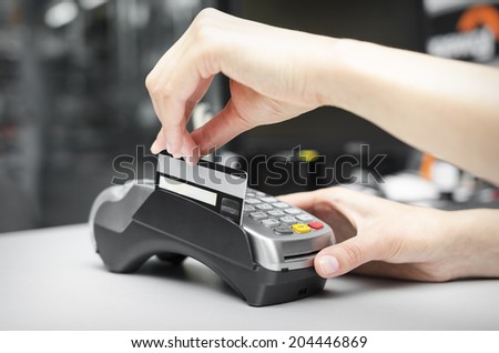 Female hand holding plastic card in bank terminal
