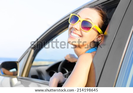 Beautiful girl in a car smiling on a background of blue sea