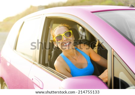 Beautiful girl in a car smiling in pink sunglasses