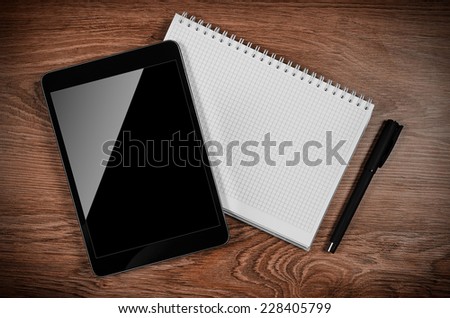 Tablet computer on the office table with notebook and pen.
