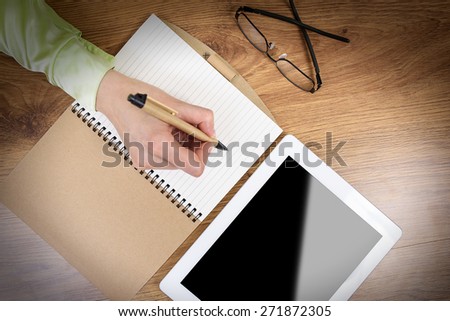 Workbook on the office desk. Tablet computer and glasses on the table.