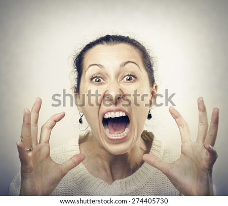 Furious woman screaming. Front view of furious brunette woman yelling at camera.