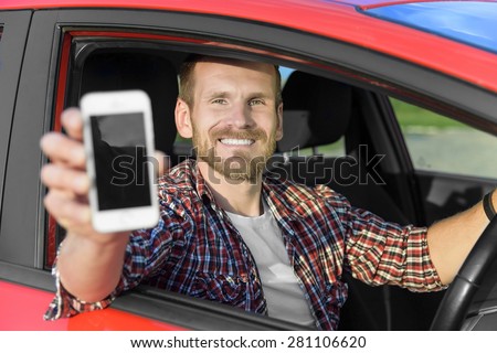 Man in car driving showing smart phone display smiling happy. Focus on model.