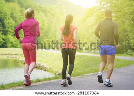 Smiling friends running outdoors. Sport fitness friendship and lifestyle concept. Back view.