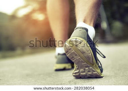 Athlete runner feet running on road closeup on shoe. Man fitness sunrise jog workout wellness concept. Toned photo.