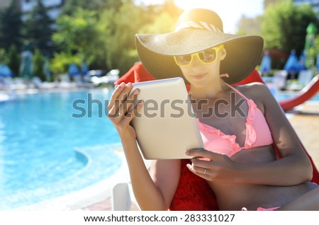 Woman holding tablet computer in the pool. Focus on tablet.