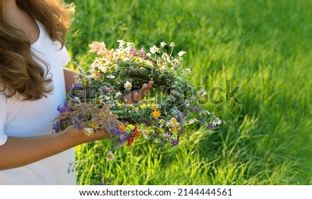 wreath of meadow flowers in hands girl, summer natural background. floral traditional decor for Summer Solstice Day, Midsummer concept. pagan witch traditions, wiccan rituals. copy space Stock fotó © 