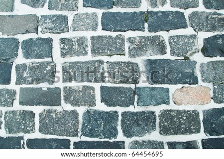 Dark blue gray background of a brick roadway from irregular stones of a stone blocks of a raw granite