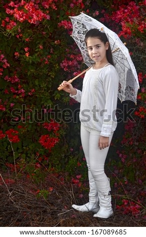 A teenage girl in white with colorful bougainvillea flowers and a white umbrella