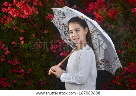 A teenage girl in white with colorful bougainvillea flowers and a white umbrella