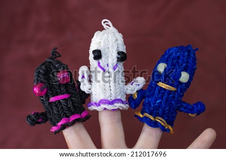 A child\'s hand decorated with original ghost dolls in blue, black, and white made using loom rubber bands