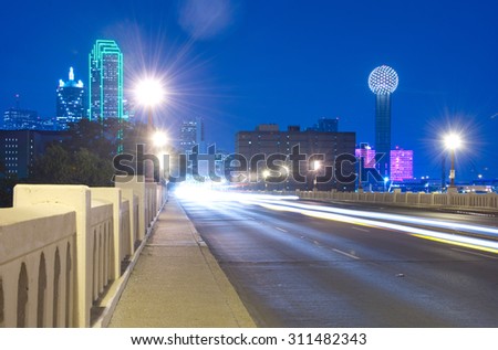 Downtown Dallas, Texas skyline at night including the famous towers, taken from the Commerce Street Bridge featuring car light trails