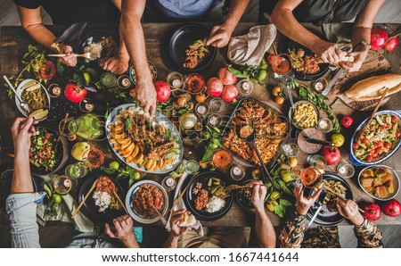 Flat-lay of family feasting with Turkish cuisine lamb chops, quince, bean, vegetable salad, babaganush, rice pilav, pumpkin dessert, lemonade over rustic table, top view. Middle East cuisine