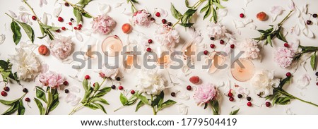 Rose wine variety layout. Flat-lay of rose wine in various glasses with flowers and summer fruit over plain white background, top view. Summer drink for party, wine shop or wine tasting concept