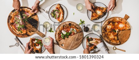 Pizza party for friends or family. Flat-lay of various pizzas, drinks and peoples hands eating pizza over plain white table background, top view. Fast food, comfort food, Italian cuisine concept