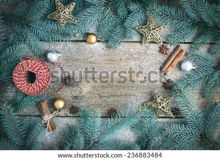 Christmas (New Year) decoration background: fur-tree branches, glass balls, golden glittering toy stars, decoration rope, cinnamon sticks and anise stars on a rough wooden desk with a copy space