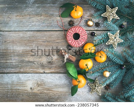 Christmas (New Year) decoration background: fur-tree branches, glass balls, golden  toy stars, cinnamon sticks, anise stars and fresh mandarins on a rough wooden desk with a copy space. Top view