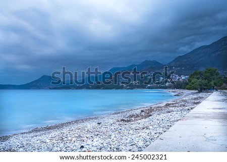 The landscape of the Adriatic coast of Bar, Montenegro before the storm: nasty dramatic sky, calm sea and misty mountains at the backdrop