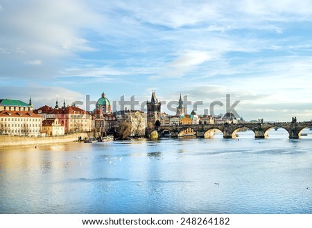 The view over the Vltava river, Charles bridge and white swans from Mala Strana in Prague, Czech Republic, on a clear sunny winter day