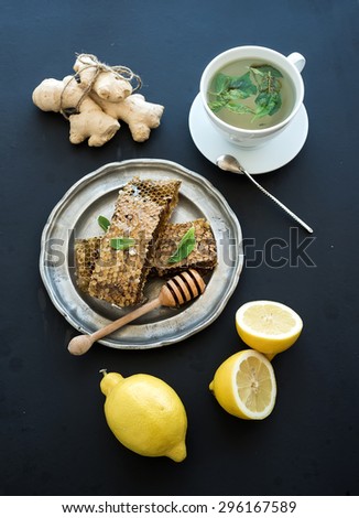 Cup of herbal tea with fresh mint, honey, lemon, ginger on grunge black  background. Top view