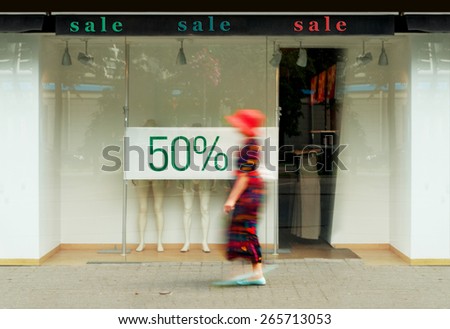 Sale signs in the shop window. Blurred figure of a woman