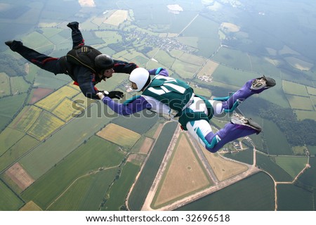 Two skydivers in freefall holding hands