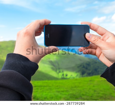 Woman hands holding smart phone, making photo of nature.