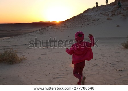 Little girl running towards to setting sun