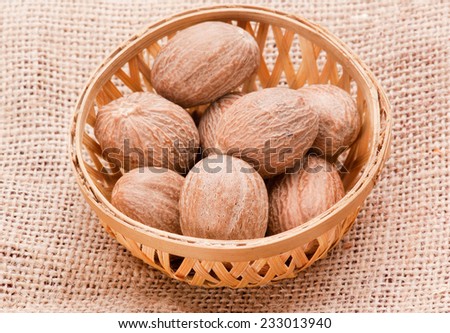 Nutmeg in basket on jute background