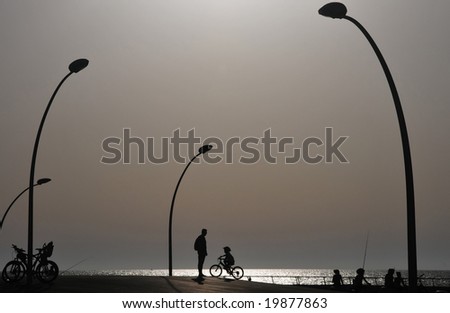 Father and son with bicycle on the boardwalk at sunset