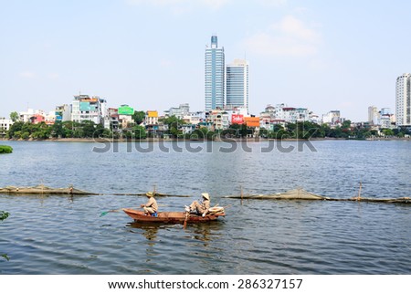 Hanoi, Vietnam - May 20 : Vietnamese men in a boat clean West lake on May 20, 2015 in Hanoi, Vietnam