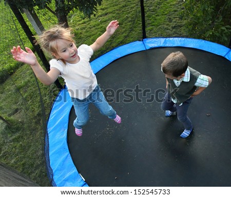 Two funny kids jumping on a outdoor trampoline.