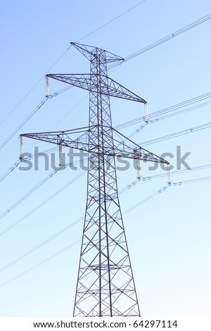 High voltage power tower and electrical lines against blue sky.