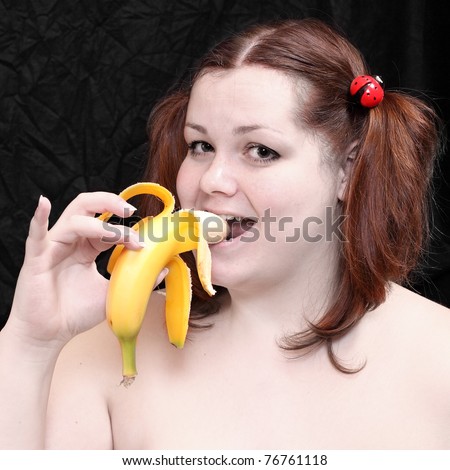Overweight woman eating fresh ripe bananas on black background.