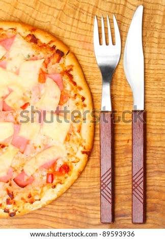 Tasty Ham and Pineapple Pizza with knife and fork.
