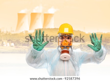 Worker in gas mask and protective suit against a radioactive air pollution from nuclear power plant.