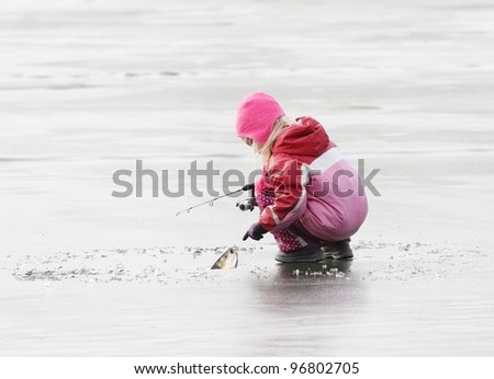 Little fisherman catching a fish on ice.