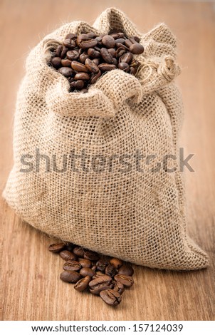 Coffee beans in coffee bag made from burlap on wooden