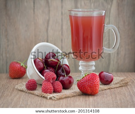 Red fruit drink with fresh red fruits on an old wooden table