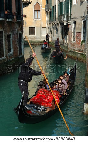 VENICE, ITALY - MARCH 11,2011: A gondolier takes Japanese tourists through the Venice canals.  Venice is one of most popular attractions in Italy and it is also a Unesco heritage site.