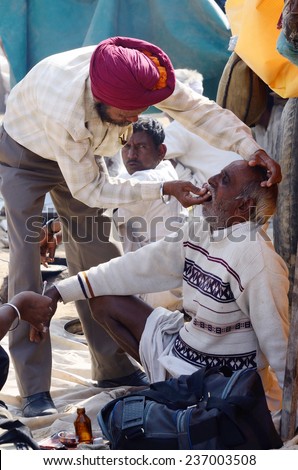 PUSHKAR, INDIA - NOVEMBER 13:Unidentified Sikh dentist treats old man teeth during traditional camel fair at Pushkar, on November 13,2013 in Pushkar, Rajasthan, India.It\'s largest camel fair in Asia