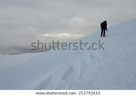 Lonely photographer with tripod making winter trekking on Gimba mountain during great snow storm ,Transcarpathian,Western Ukraine, overcast weather