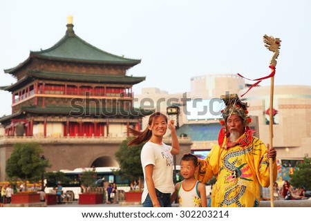 On July 29, 2015, xi \'an, in the clock tower scenic area, a wore a crown, dragon robe, a old man play the part of the emperor, in sorching burning sun, free and tourists.
