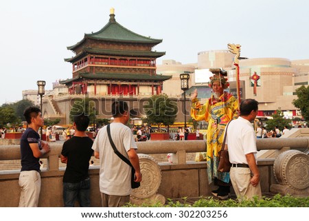 On July 29, 2015, xi \'an, in the clock tower scenic area, a wore a crown, dragon robe, a old man play the part of the emperor, in sorching burning sun, free and tourists.